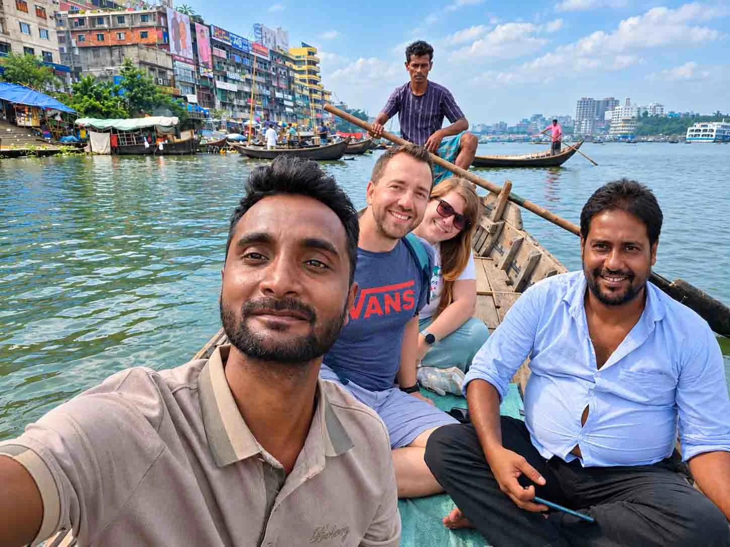 Travelers enjoying a traditional wooden boat ride during an Old Dhaka tour, experiencing the Buriganga River and the vibrant riverside life of Bangladesh.