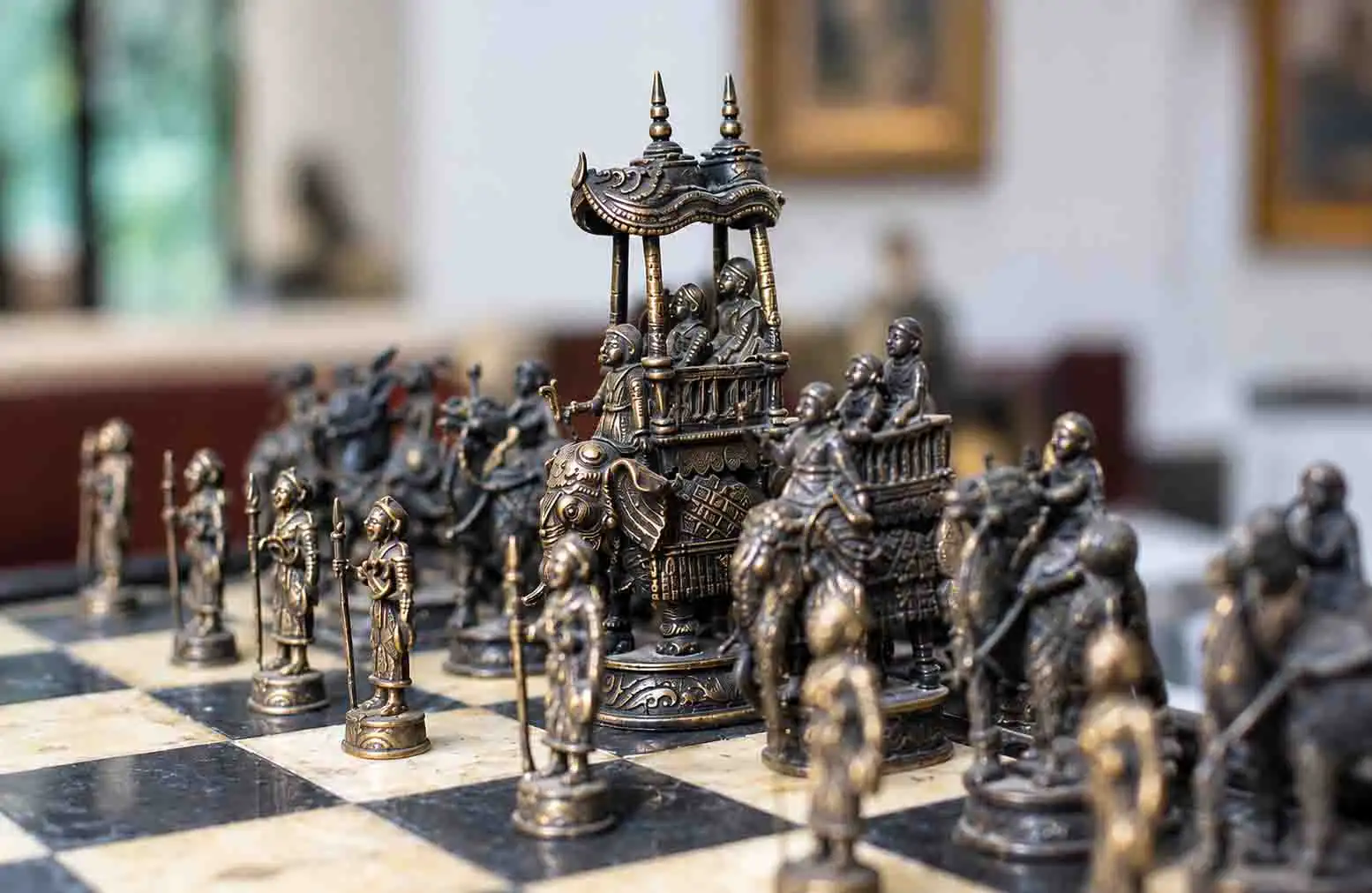 Intricately crafted antique metal chess pieces displayed on a checkered board, highlighting traditional metal artistry.