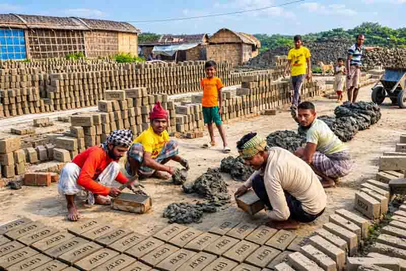 Workers making and arranging clay bricks at a traditional brick-making site in Bangladesh.